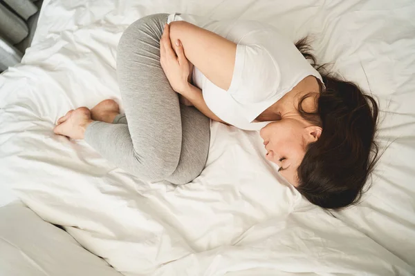 Vrouw met gesloten ogen liggend in foetale positie — Stockfoto
