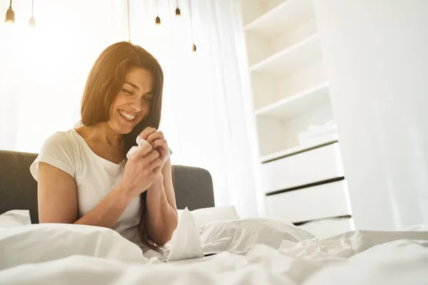 Alegre hermosa dama en una camiseta sentada en la cama — Foto de Stock