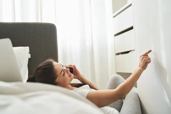 Mujer con un gadget acostado en la cama — Foto de Stock