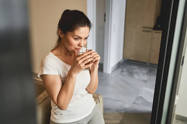 Задумчивая женщина пьет травяной чай дома — стоковое фото