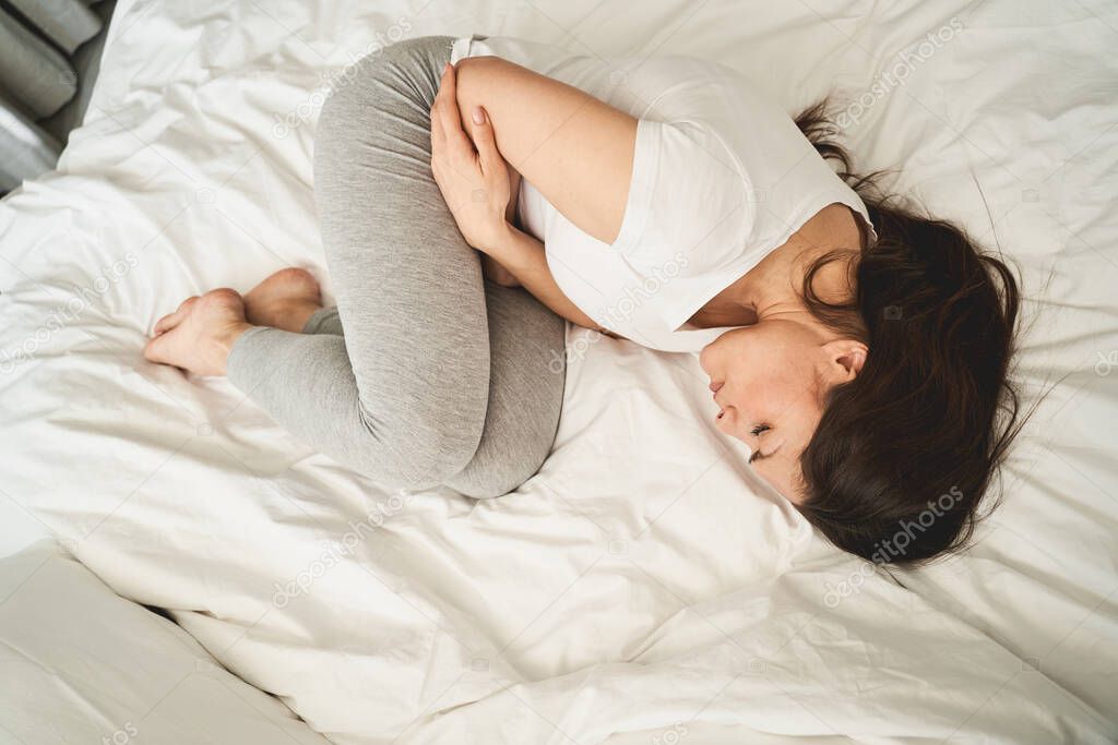 Woman with closed eyes lying in a fetal position