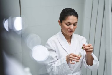 Kadın elinde bir güzellik ürününe bakıyor.