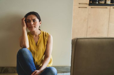 Yere bakan yansıtıcı bakışlı bir kadın.