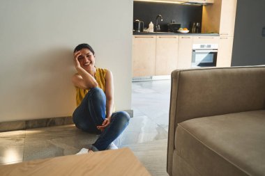 Gülen kadın fayansta oturuyor.