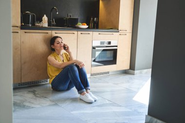 Mutfakta bir kadın telefon görüşmesi yapıyor.