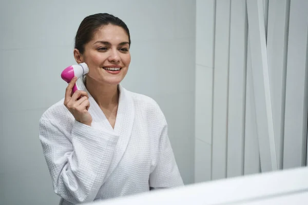 Alegre dama limpiando su piel ante el espejo —  Fotos de Stock