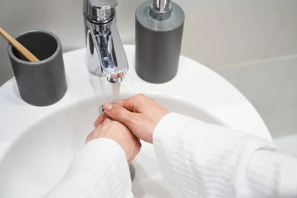 Bornozlu bir kadın el yıkama işlemi yapıyor. — Stok fotoğraf