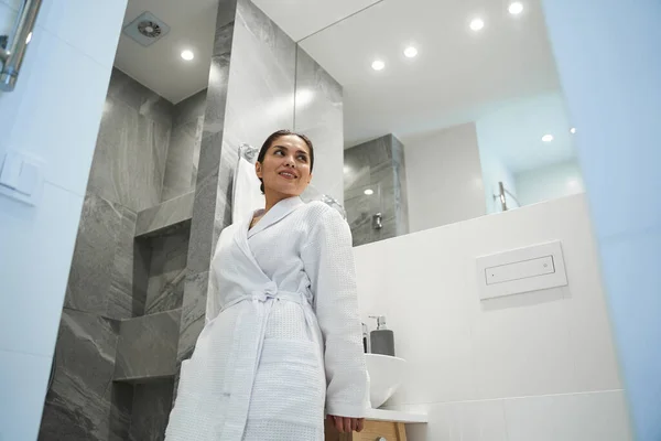 Zufriedene süße Frau lehnt an der Arbeitsplatte im Badezimmer — Stockfoto