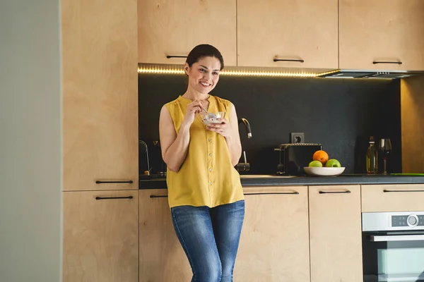 Sonriendo encantadora dama apoyada contra la encimera en el desayuno —  Fotos de Stock