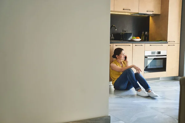Женщина разговаривает по телефону на кухне — стоковое фото