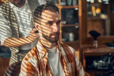 Berber dükkanı müşterisi berberinin saçını kesmesini bekliyor.