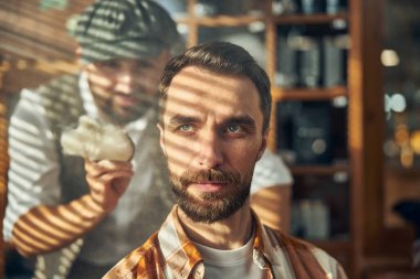 Gri gözlü sakallı hippi saçını kestirmek için bekliyor.