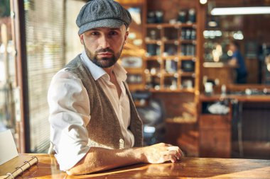 Berber dükkanında eski moda şapka takan yakışıklı bir kuaför.