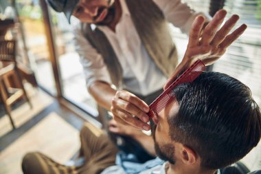 Hevesli saç stilisti müşterisine yeni bir görünüm kazandırmaya çalışıyor.