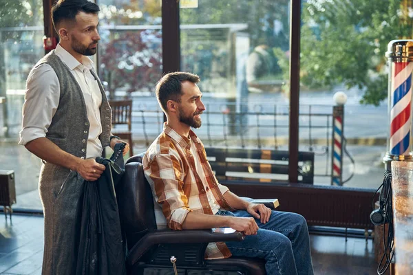 Barbeiro qualificado e seu cliente olhando no espelho — Fotografia de Stock