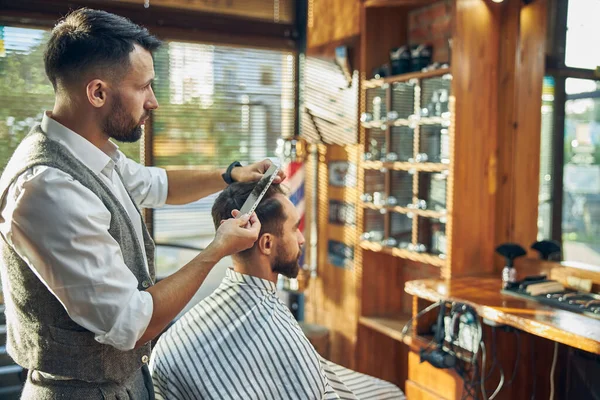 Ambitieuze kapper werkt aan een knipbeurt van zijn bezoeker — Stockfoto