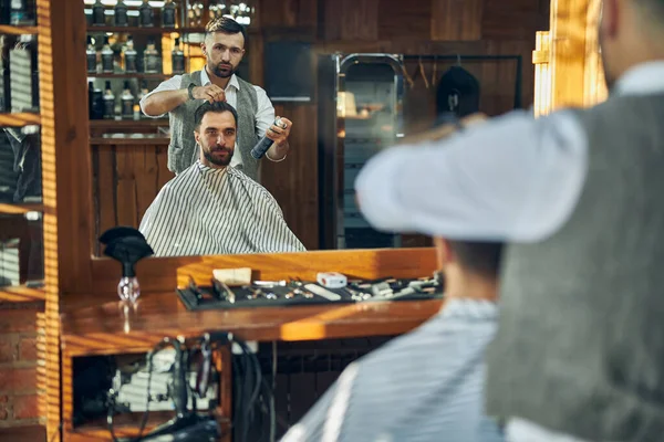 Vakkundige kapper met een klant in zijn salon — Stockfoto