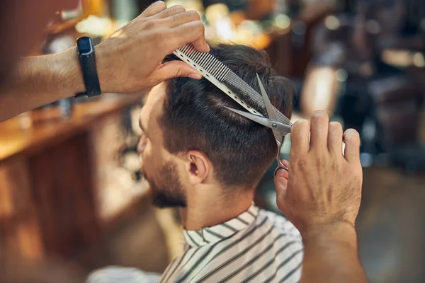 Bir kuaförde saçını kestirip şekillendiren genç bir adam.
