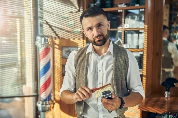 Profesyonel saç stilisti elektrikli makasını temiz ve düzenli tutuyor.