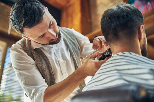 Profesjonalny fryzjer patrząc na włosy klienta — Zdjęcie stockowe