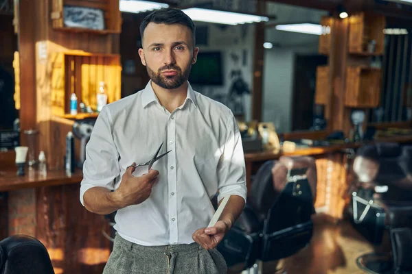 Giovane parrucchiere che guarda professionale al suo posto di lavoro — Foto Stock