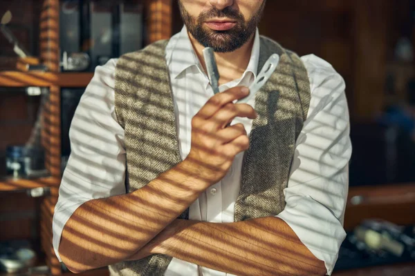 Peluquero experto posando con una navaja de afeitar en una barbería — Foto de Stock