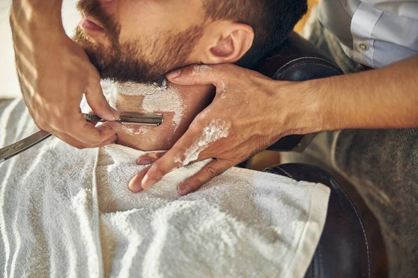 Sakallı adam berber dükkanında yeni tıraş oluyor.