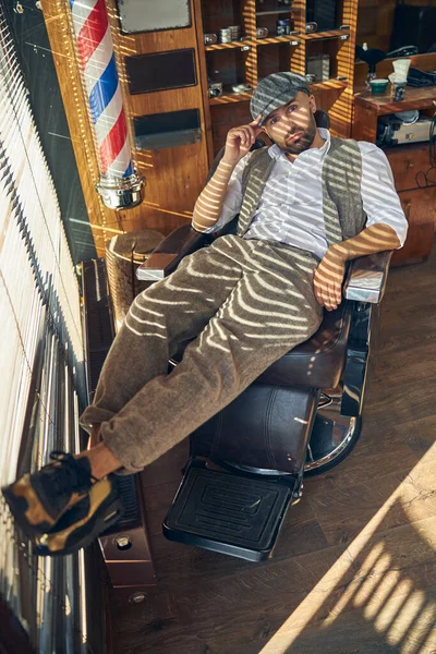 Well-dressed brunette man sitting laid-back in a barber chair — Stock Photo, Image