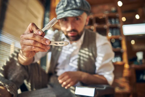 Hair-stylist wearing a peaky hat and holding a razor — Stock Photo, Image