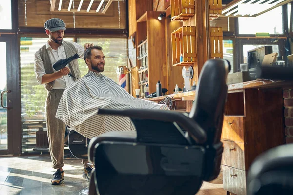 Γκλάντσομ άντρας σε πολυθρόνα να στεγνώνει τα μαλλιά του — Φωτογραφία Αρχείου