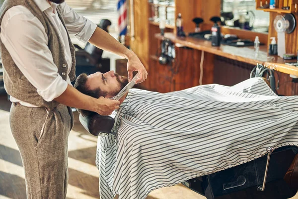 Jonge klant in een kapperszaak krijgt zijn baard verzorgd — Stockfoto
