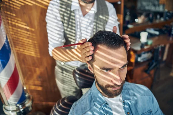 Vakkundige kapper het aanpassen van zijn klant hoofd voor styling haar — Stockfoto