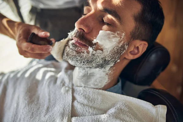 Uvolněný muž pokrytý krémem na holení ve kadeřnictví — Stock fotografie