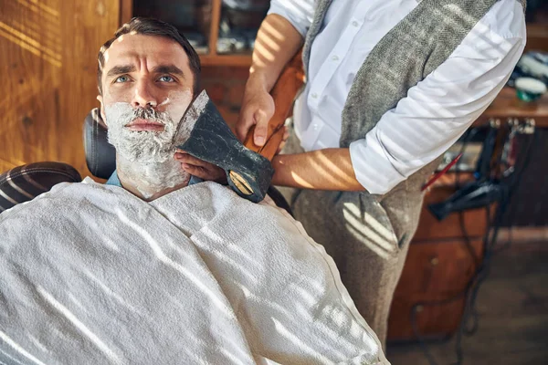 Обеспокоенный клиент парикмахерской, которого брили топором — стоковое фото
