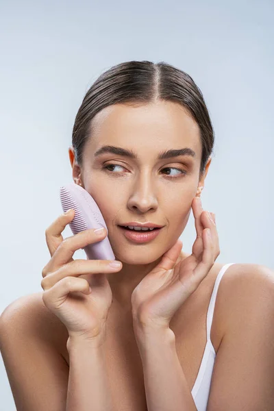 Mulher atraente usando mini escova de massageador de limpeza elétrica para rosto — Fotografia de Stock