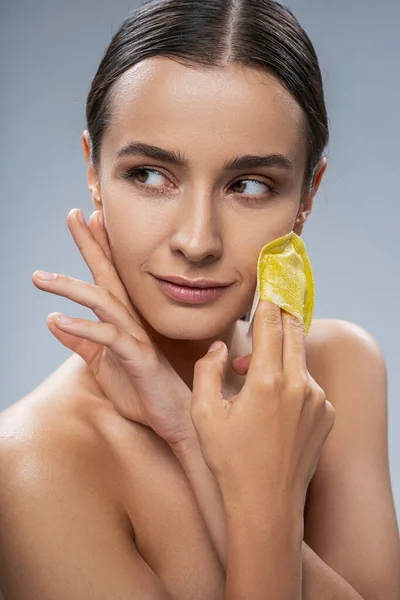 Elegante donna che utilizza la spugna per il trucco mentre pulisce la sua pelle del viso — Foto Stock