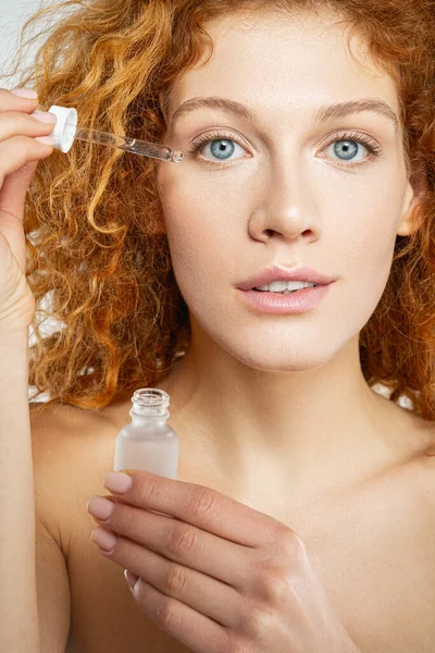 Bottiglia di vetro di olio con una pipetta o siero viso in mano donna — Foto Stock