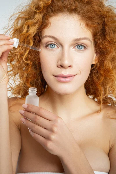 Mulher colocando creme no rosto sob os olhos — Fotografia de Stock