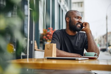 Memnuniyet duyan bir adam şehirde hoş bir telefon konuşması yapıyor.