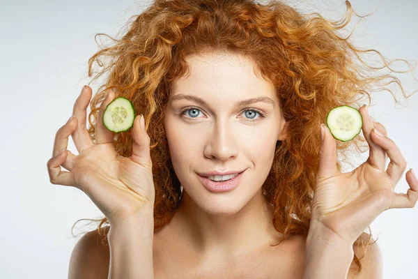 Gelukkig jong vrouwtje met plakjes komkommer in de handen — Stockfoto