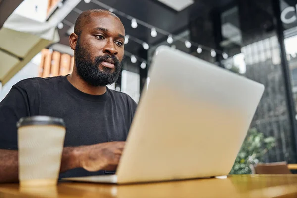 Homem concentrado trabalhando online no café — Fotografia de Stock