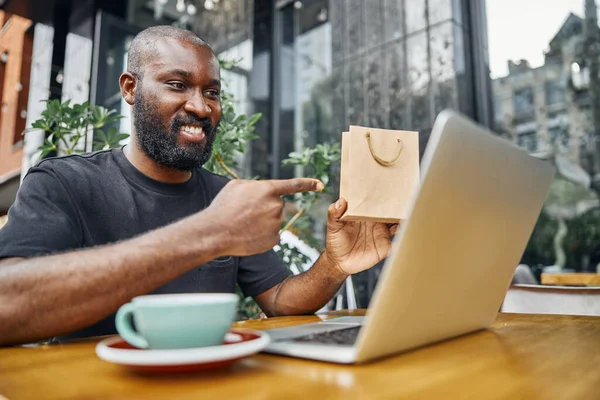 Glimlachende man die zijn aankoop demonstreert op de camera — Stockfoto