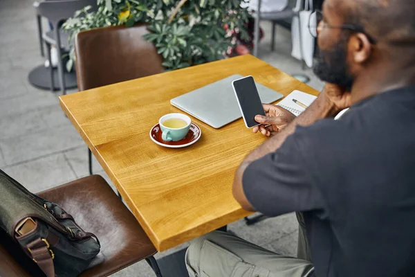 Jovem olhando para o gadget em sua mão no terraço do café — Fotografia de Stock