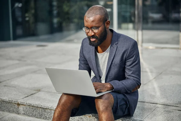 El hombre atento de piel oscura mirando la pantalla del portátil — Foto de Stock