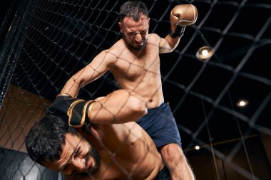 Kaslı adam yumrukların altında başını kapatıyor.