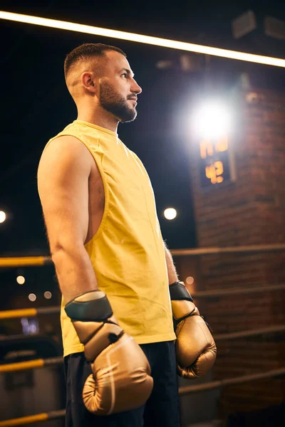 Luchador en ropa deportiva amarilla mirando algo fuera del ring — Foto de Stock