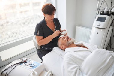 Spa terapisti yaşlı bir adam için losyon hazırlıyor.