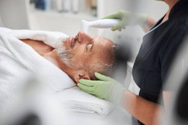 Cilt bakımı seansına katılmış yaşlı bir adam.