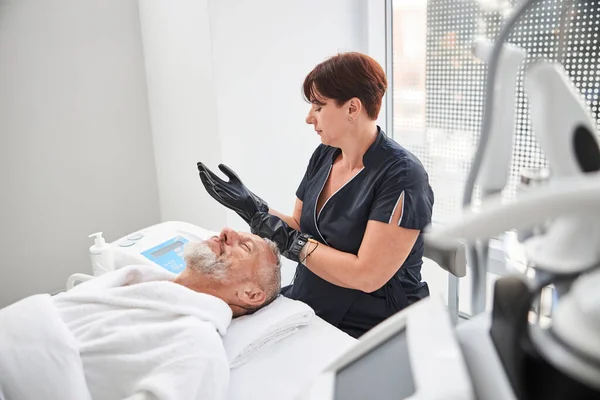 Masajista profesional usando guantes de masaje en su lugar de trabajo — Foto de Stock