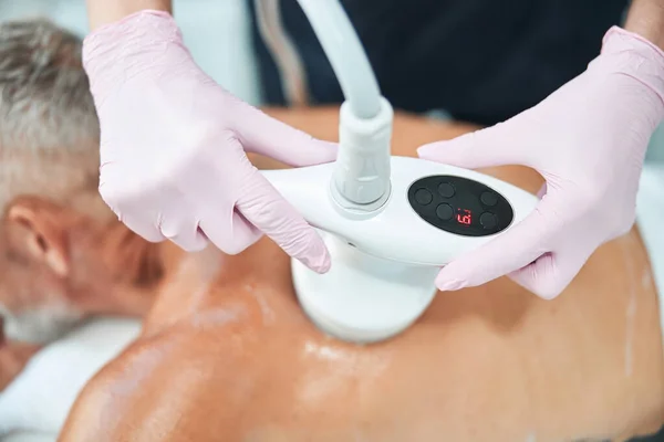 Spa-medewerker die een vetreducerende procedure uitvoert met een speciaal apparaat — Stockfoto